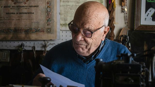 An old man with glasses reads a letter. 